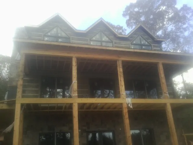 Dormers and porch framing on a large log home under construction — Roof Coating work by our crew in Franklin